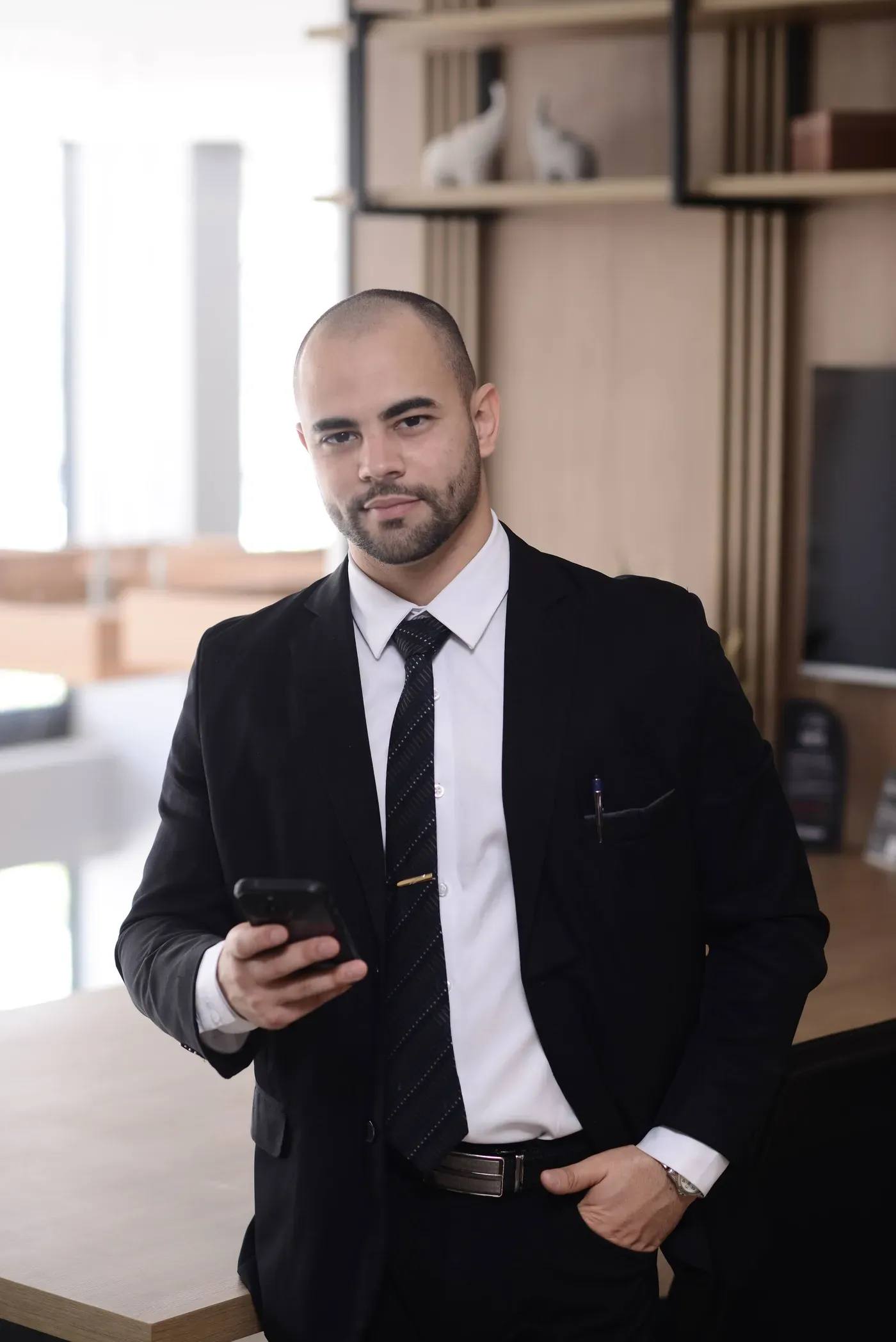 Renan Gaudereto Teixeira, advogado em casos de calúnia e difamação, com o celular na mão, olhando para a câmera