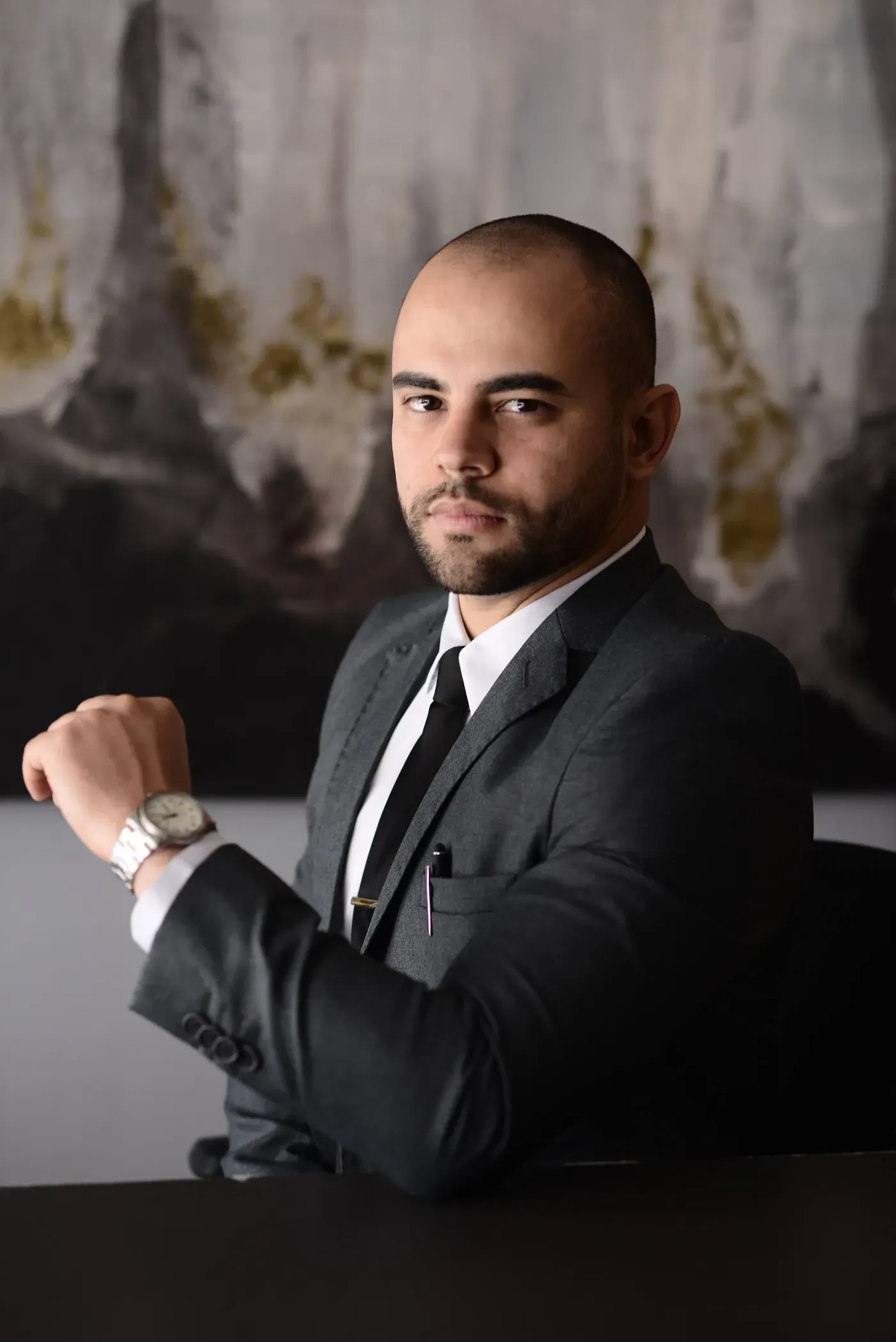 Renan Gaudereto Teixeira, advogado que acompanha vítimas de racismo, sentado no escritório, ajustando o relógio