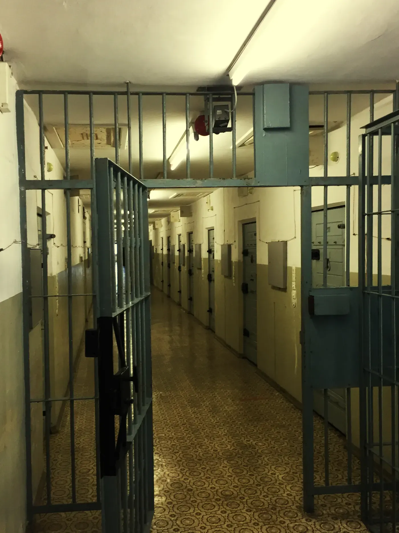 Corredor de uma unidade prisional com o portão de grades aberto