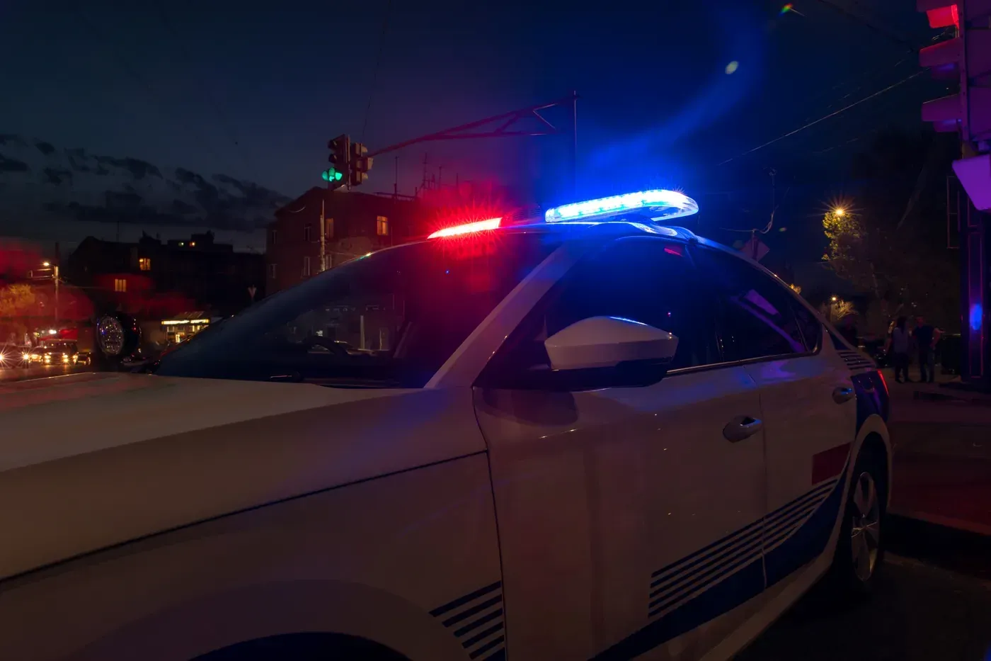 Viatura da polícia parada numa rua à noite, com o giroflex azul e vermelho aceso