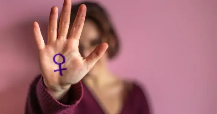 Mulher mostra a palma da mão com o símbolo feminino desenhado
