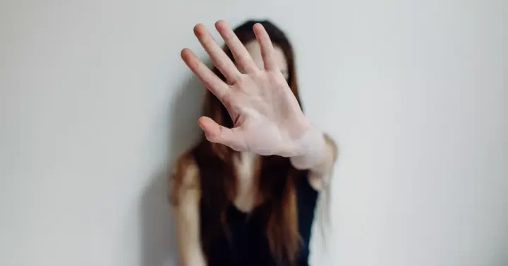 Mulher estende a mão aberta em direção à câmera em sinal de pare